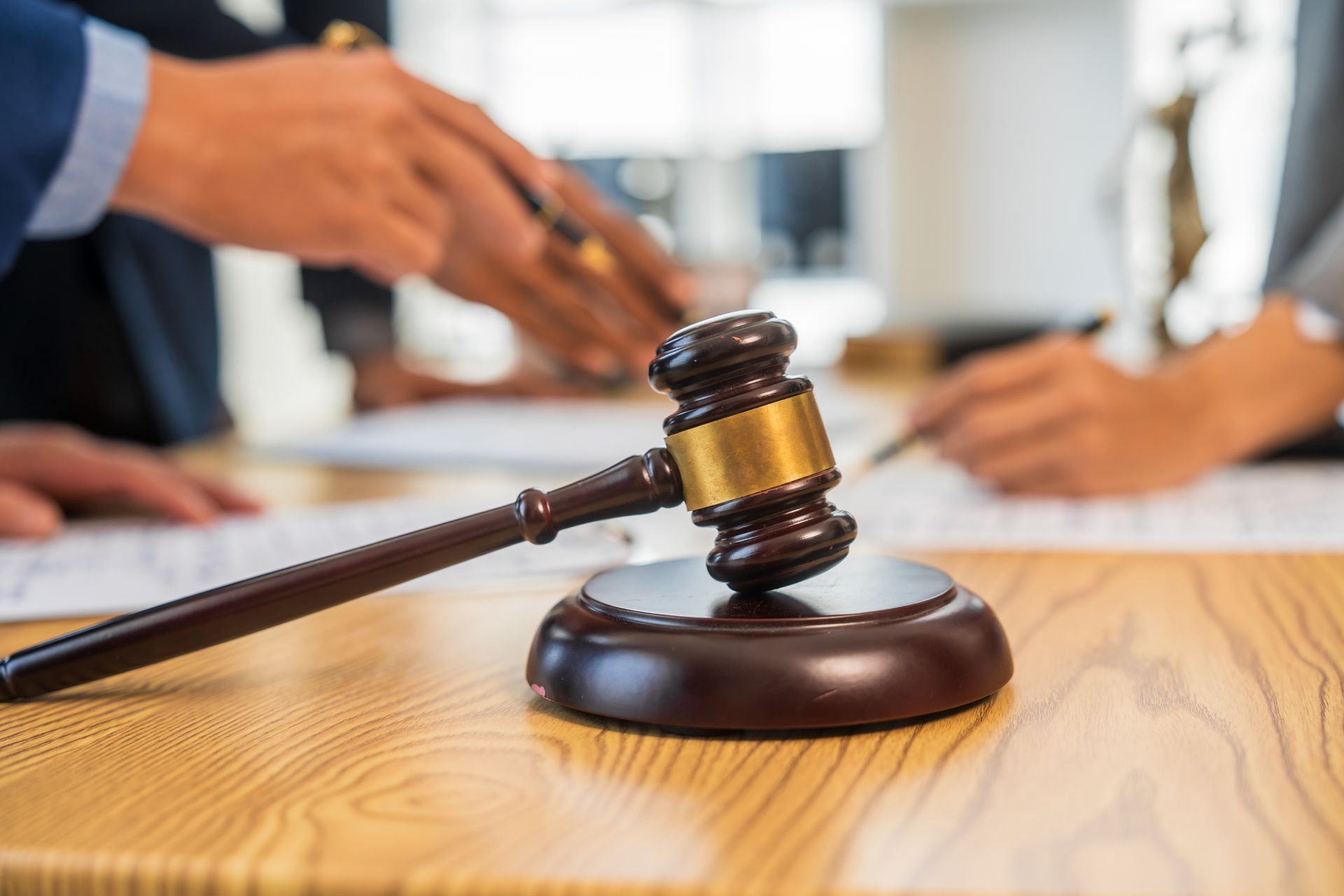 Judge’s gavel on a wooden desk with blurred hands in a courtroom setting