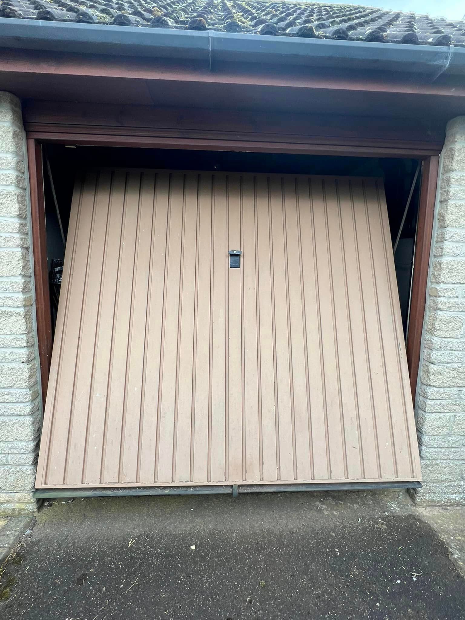 A garage door is open and a brick wall is behind it.