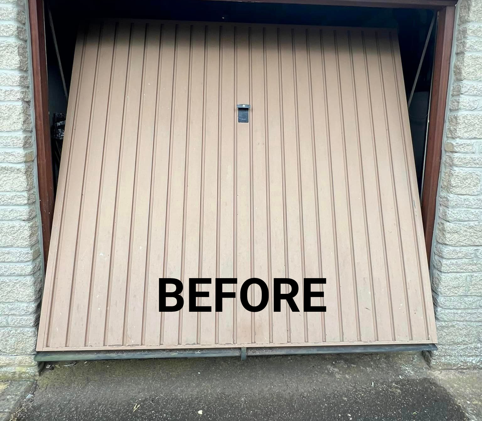 A garage door is open and a brick wall is behind it.