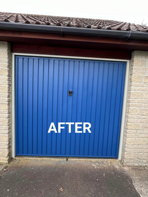 A blue garage door is sitting in front of a brick building.