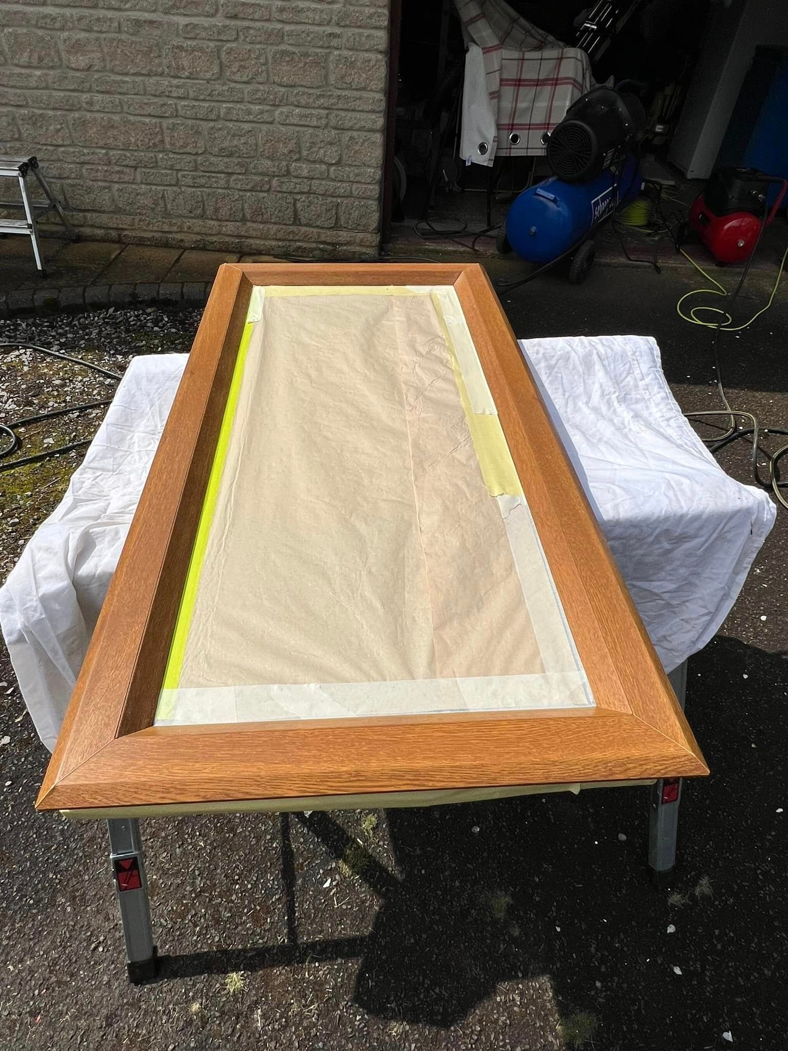 A wooden frame is sitting on top of a white table.