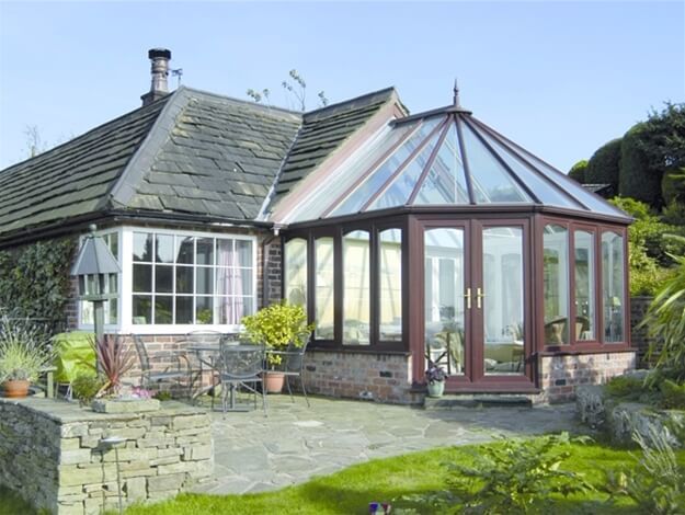Stone cottage with a glass conservatory and patio in a sunny garden