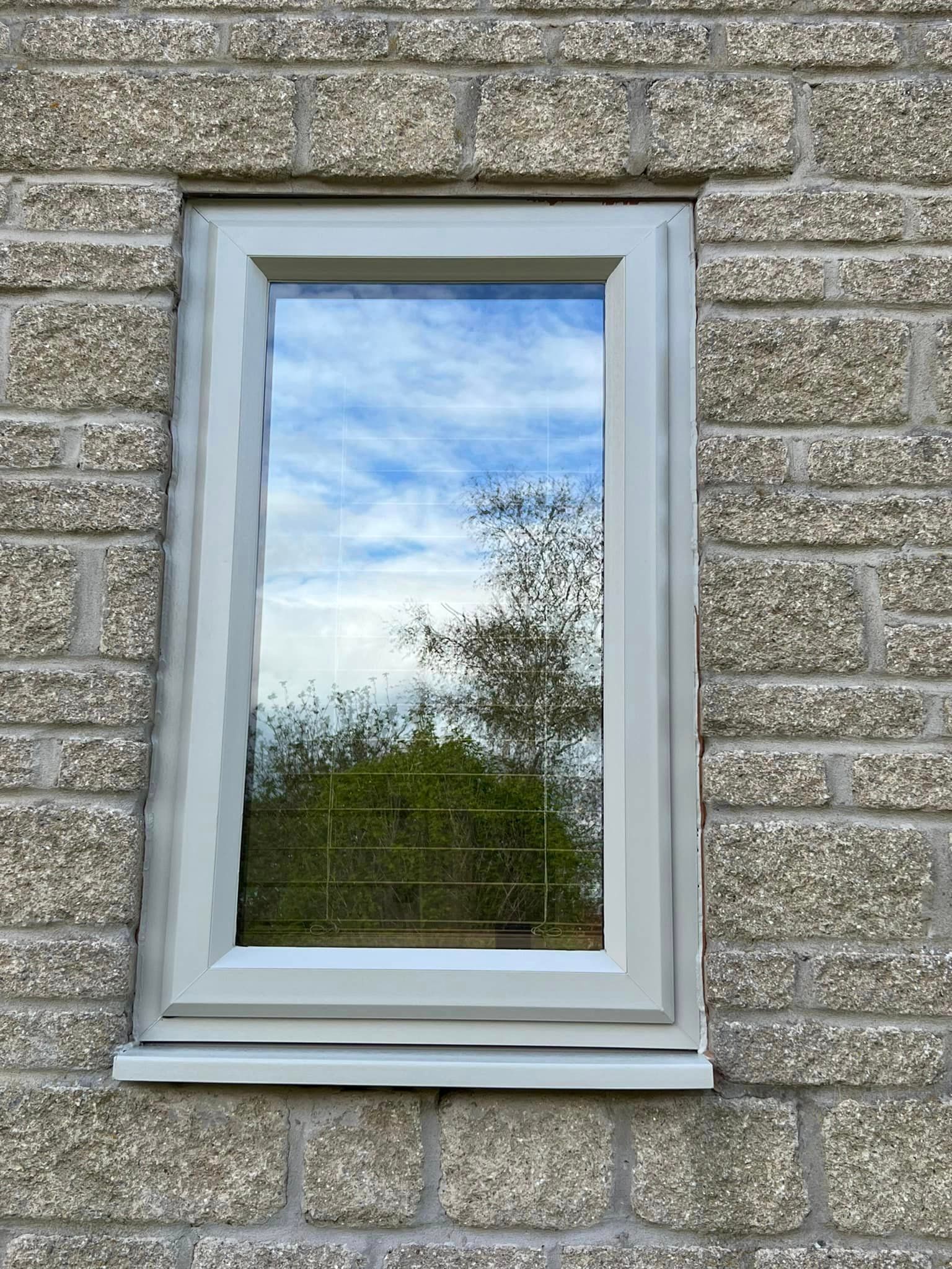 A window on a brick wall with a blue sky reflected in the window.