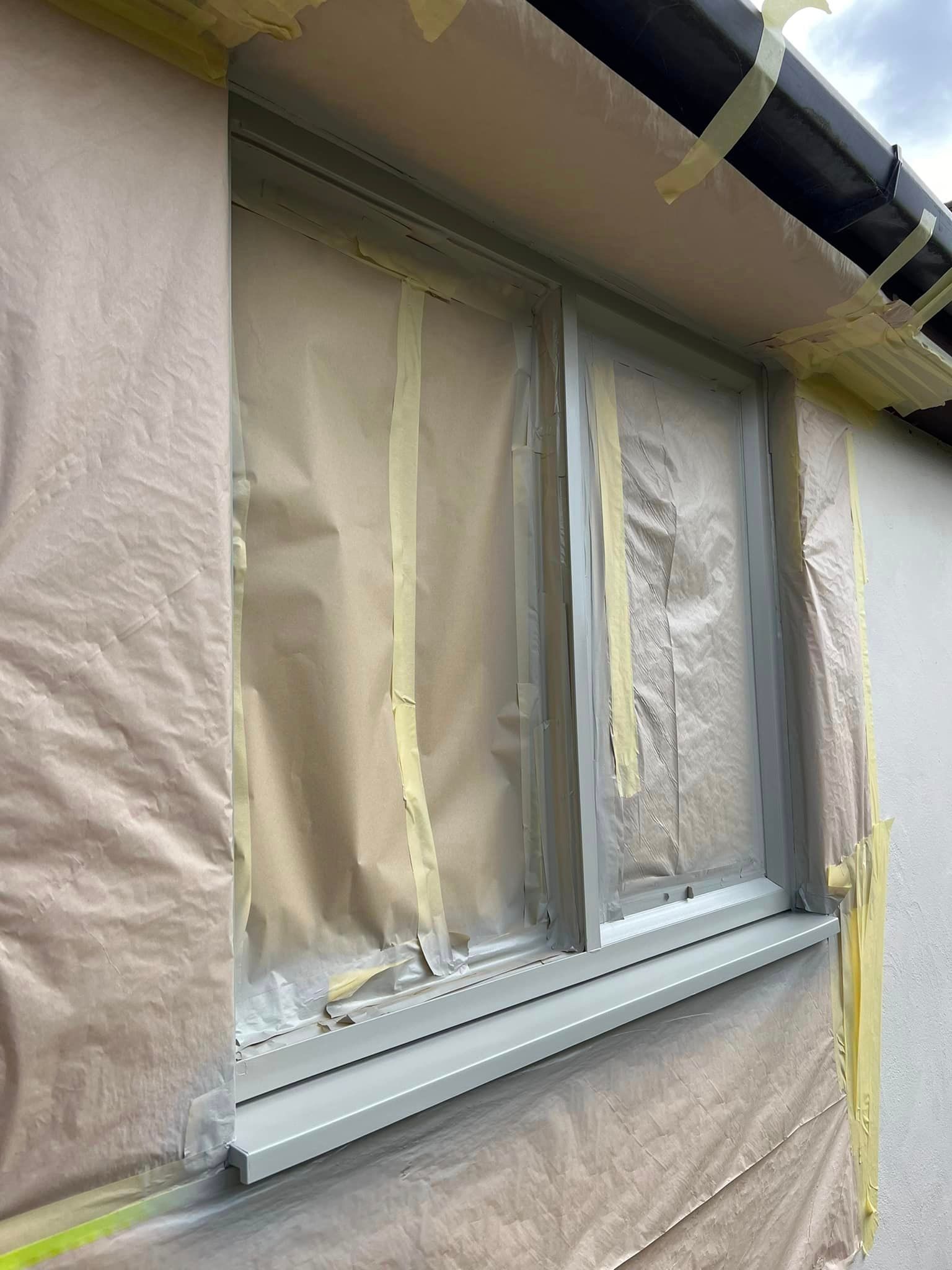 A window on the side of a building is covered in plastic and tape.