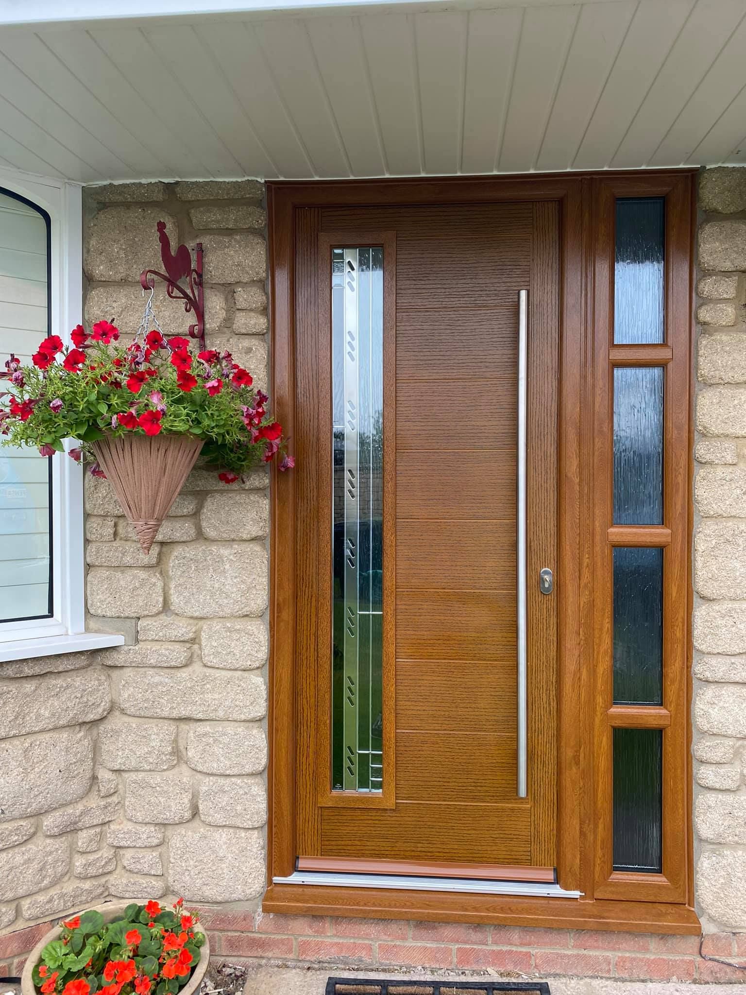 A wooden door with a stainless steel handle is on a brick wall.