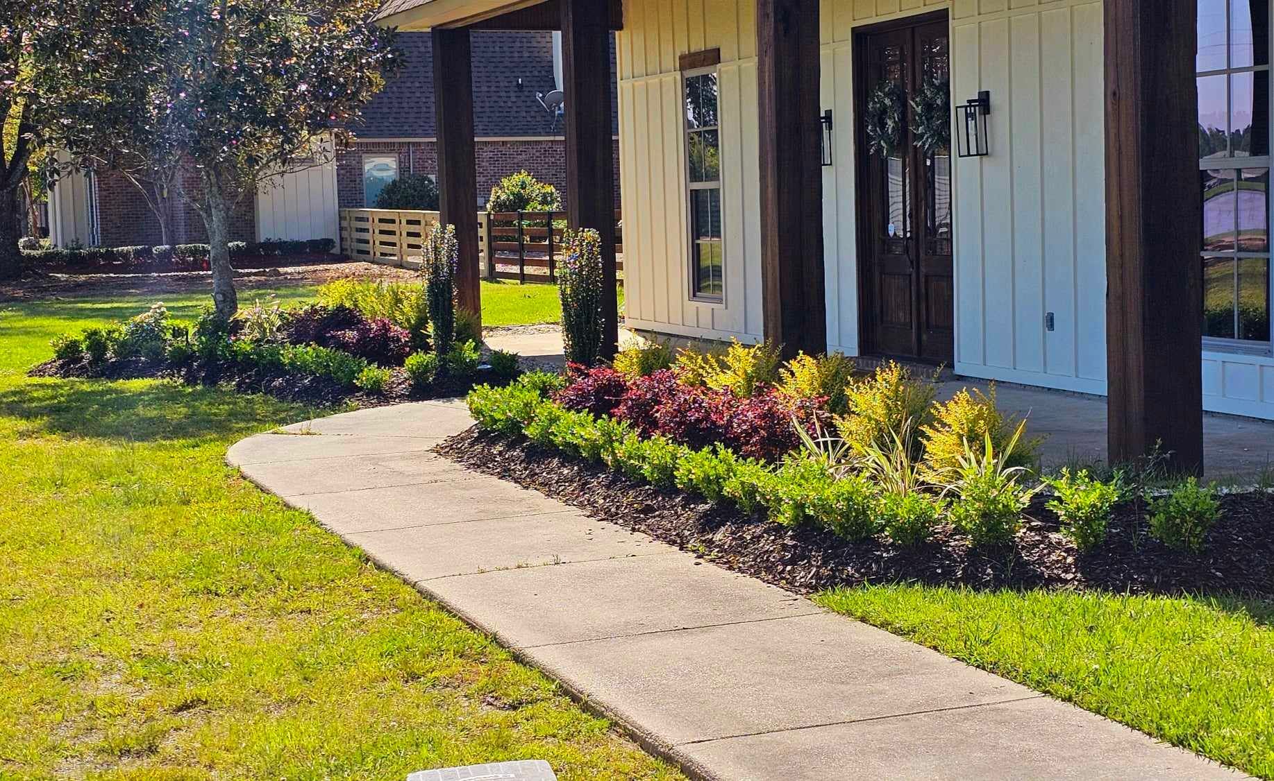 A concrete walkway leading to a white house with a porch.