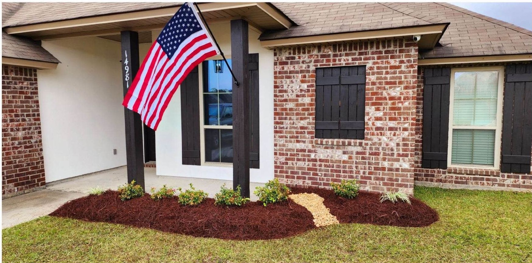 An american flag is flying in front of a brick house