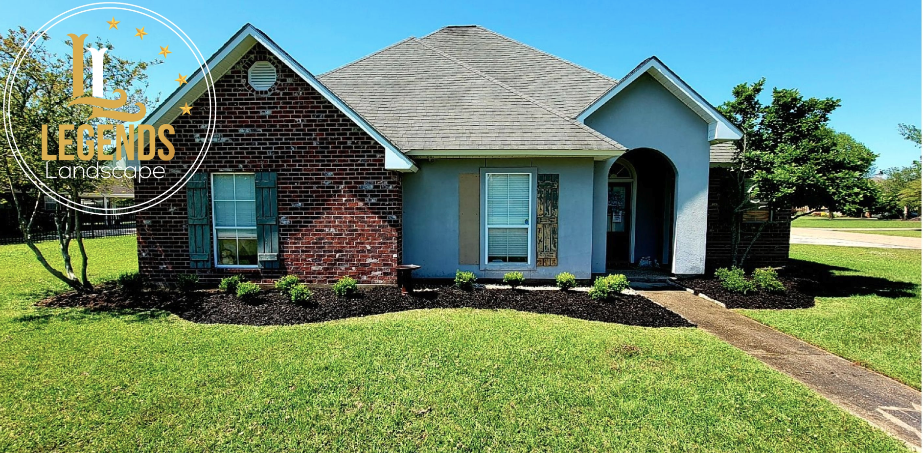 A brick house with a lush green lawn in front of it.