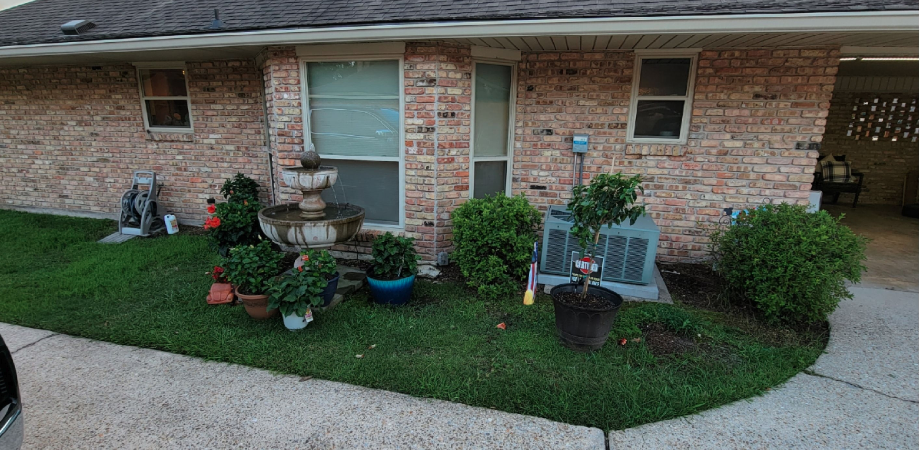 A brick house with a lot of plants in front of it.