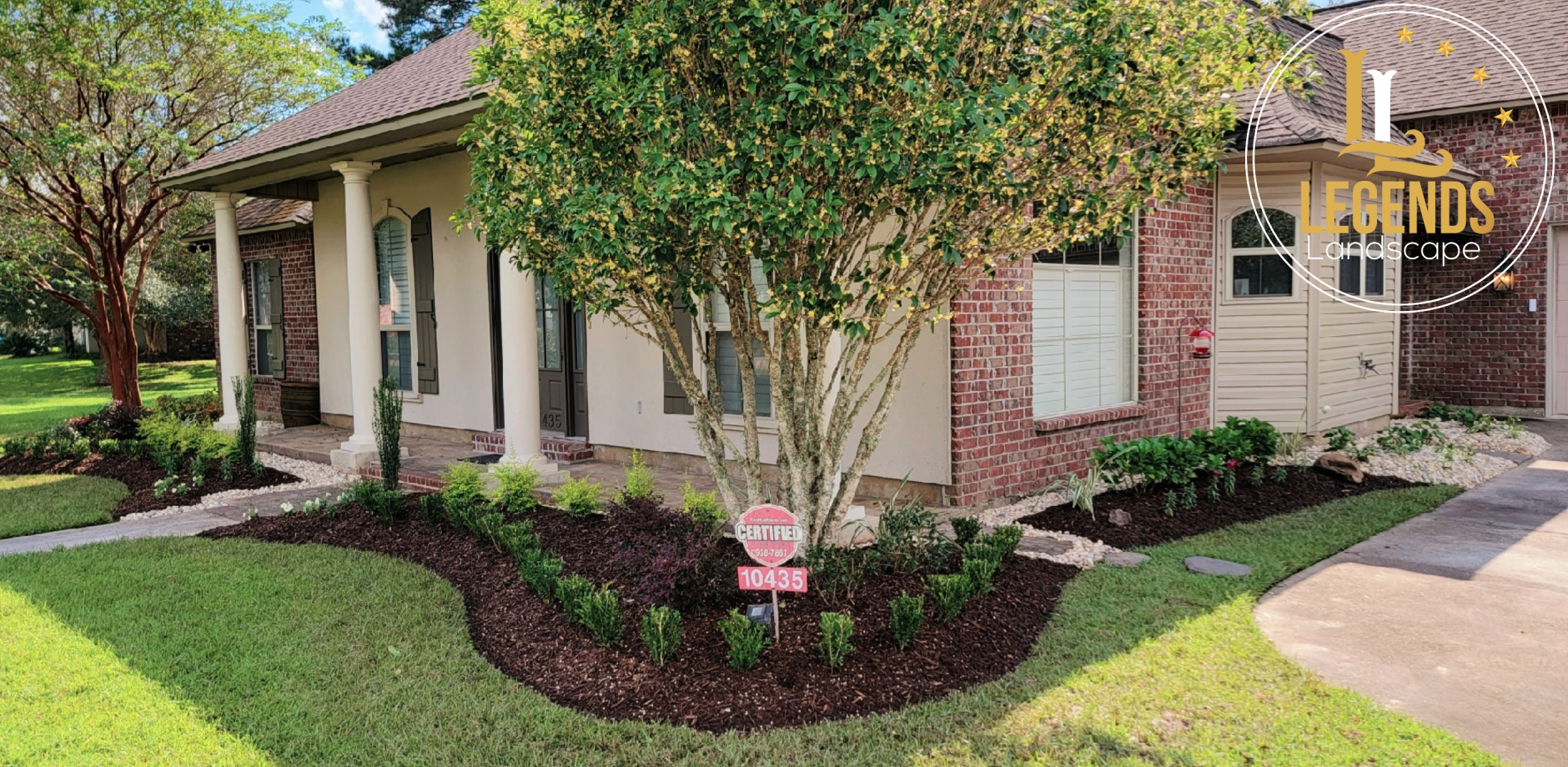 A house with a lush green lawn and a tree in front of it.
