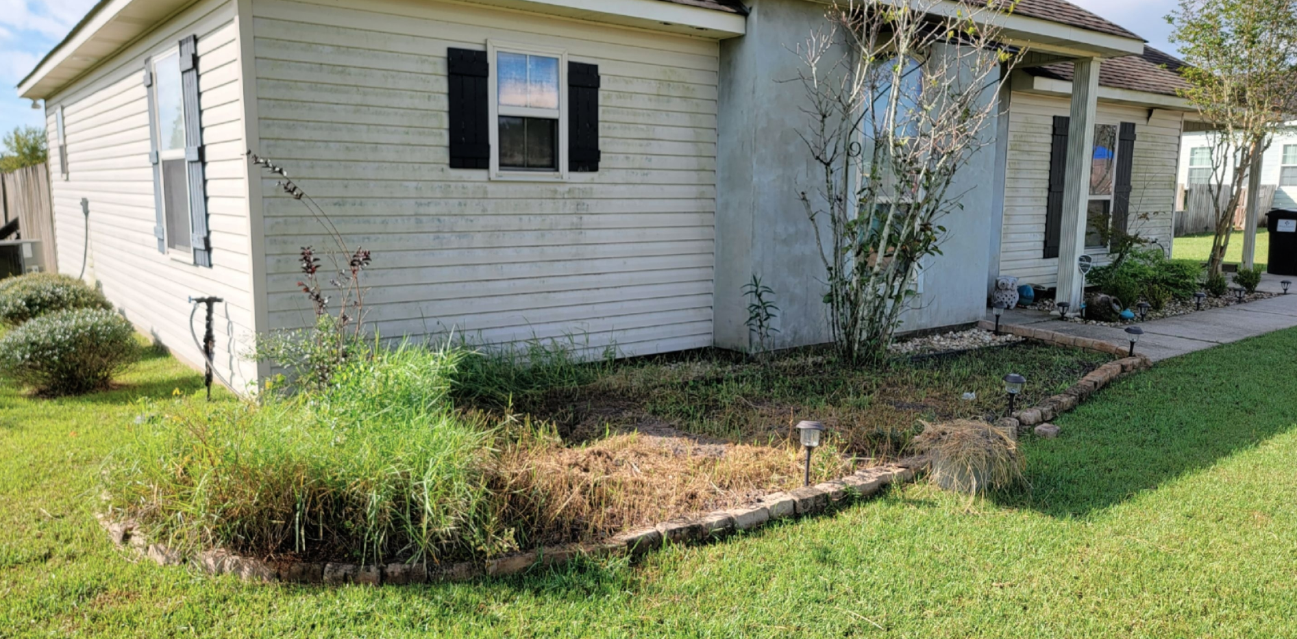 A white house with black shutters is sitting on top of a lush green lawn.