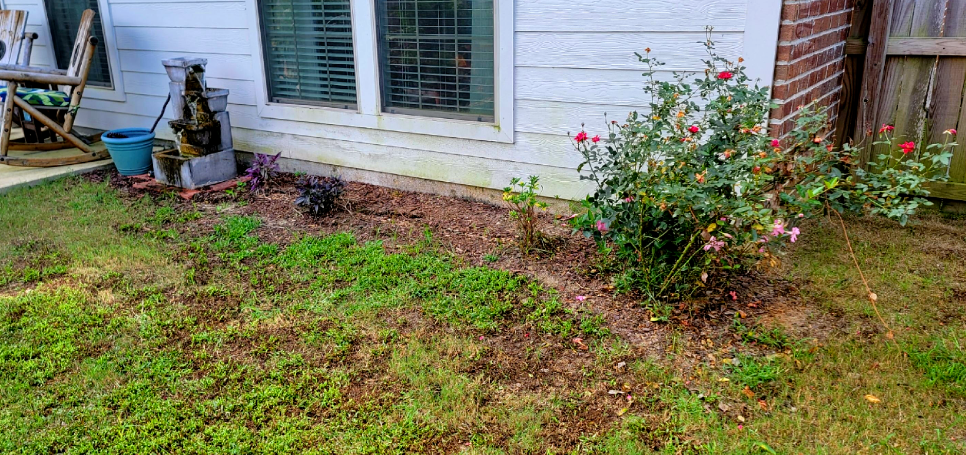 There is a rocking chair in the backyard of a house.