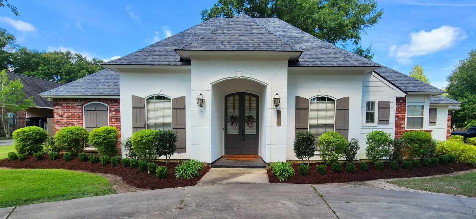 A white house with a gray roof and a driveway in front of it.