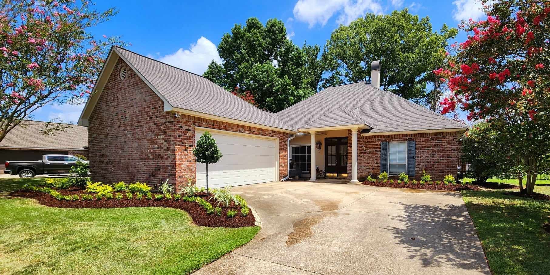 A brick house with a driveway and a truck parked in front of it.