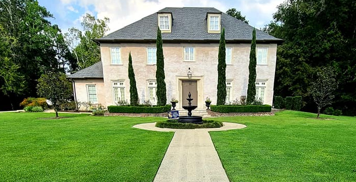 A large brick house with a fountain in front of it.
