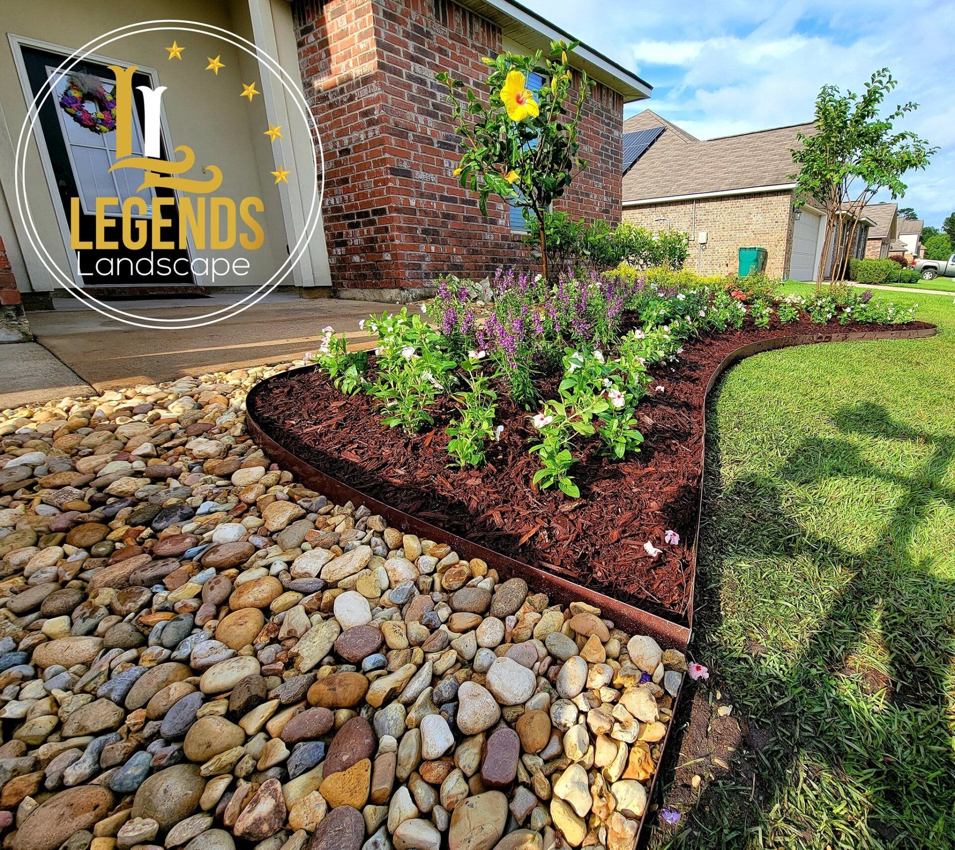 A garden with rocks and flowers in front of a house.