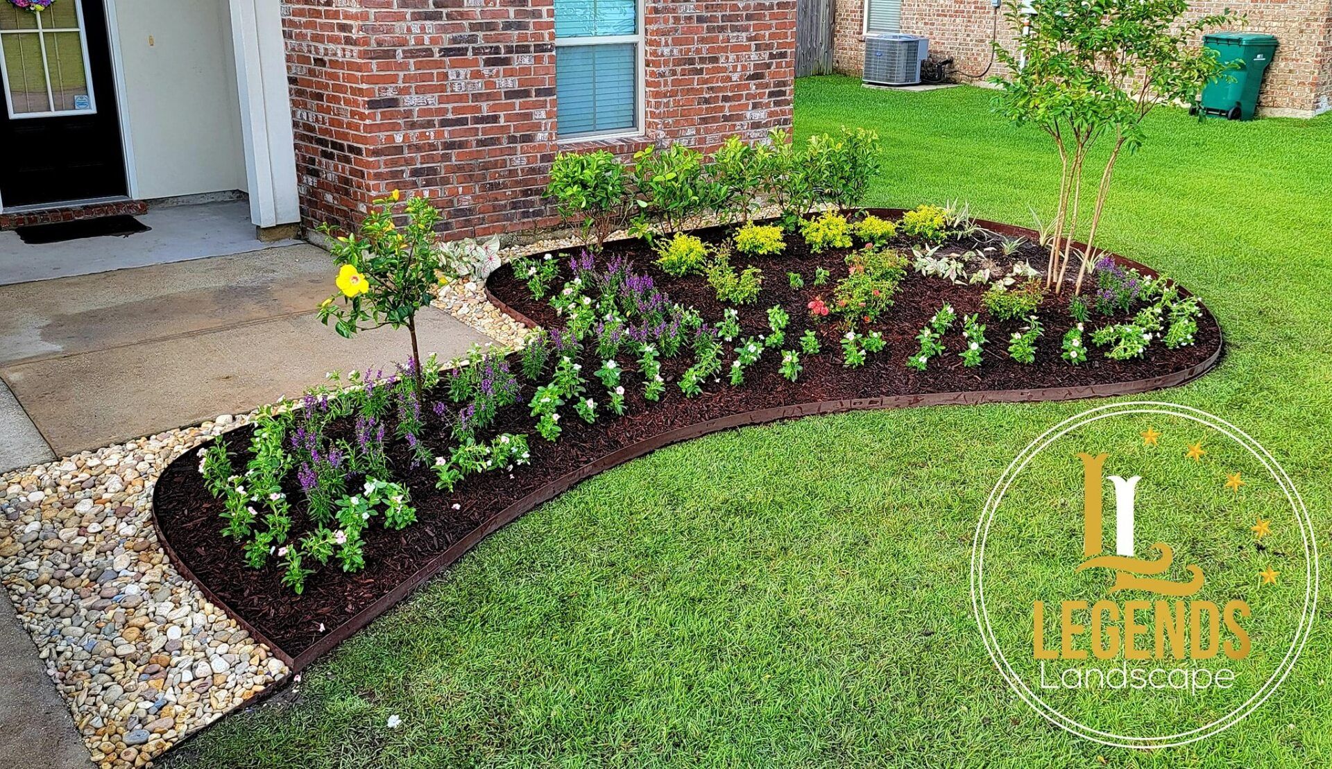 A brick house with a lush green lawn and a garden in front of it.