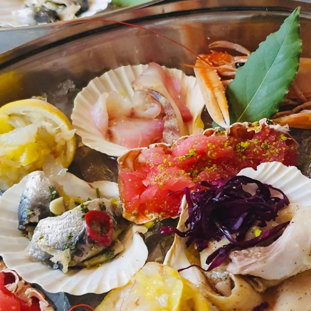 Plateau de fruits de mer sur glace : poisson cru, crevettes, homard, tranches de citron, herbes et chou rouge.