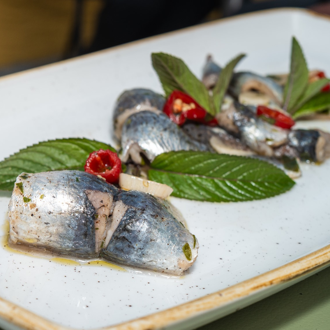 Assiette de harengs marinés, garnie d'herbes et de poivrons rouges.