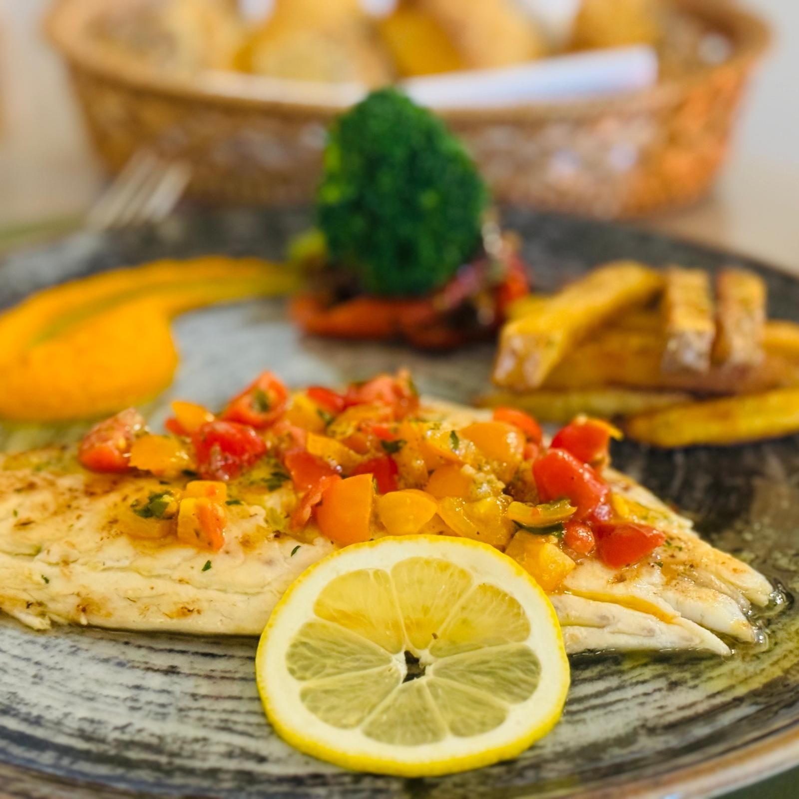 Assiette de filet de poisson avec salsa de tomates, citron, légumes et frites.
