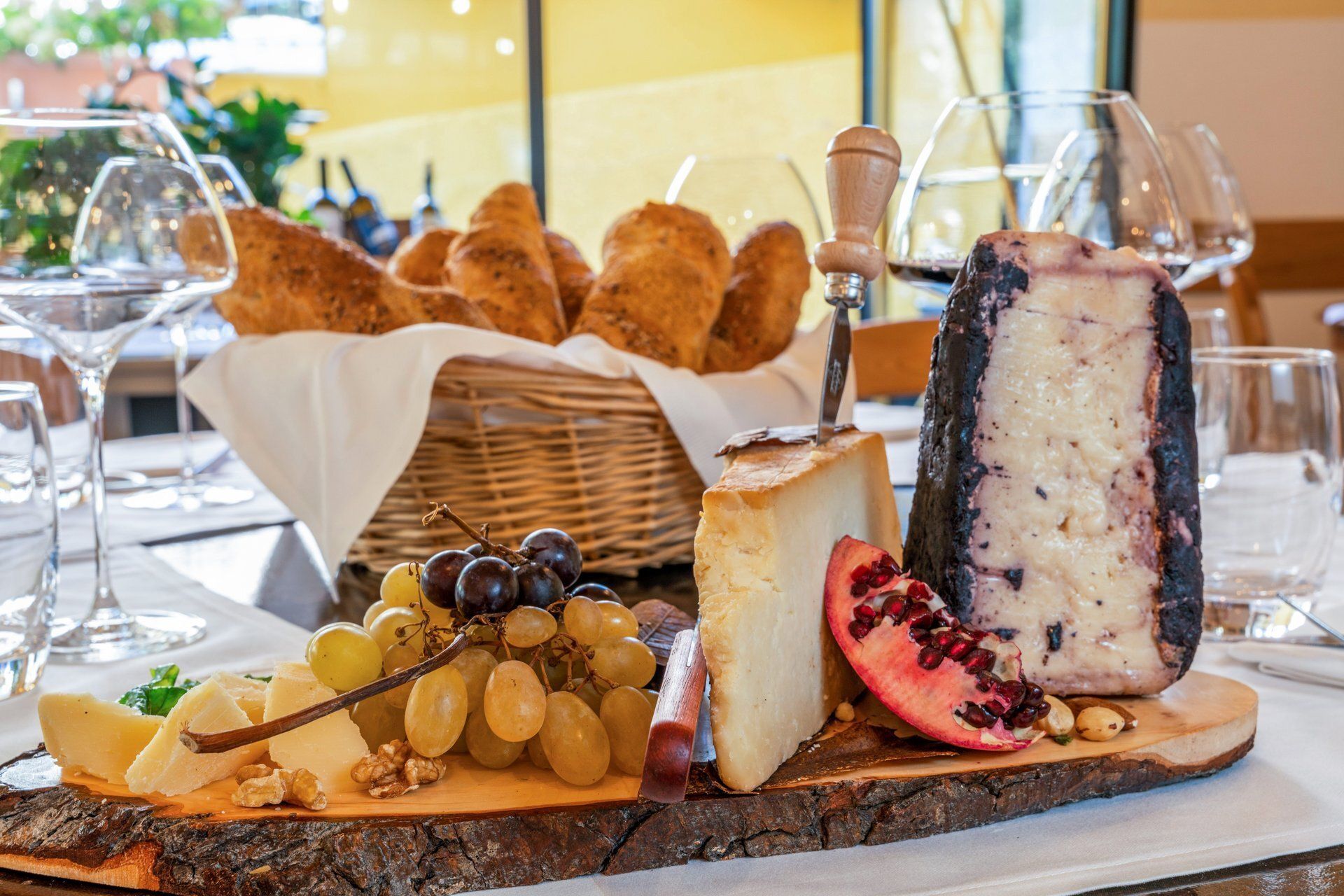 Plateau de fromages et de pains avec raisins, pain et verres à vin.