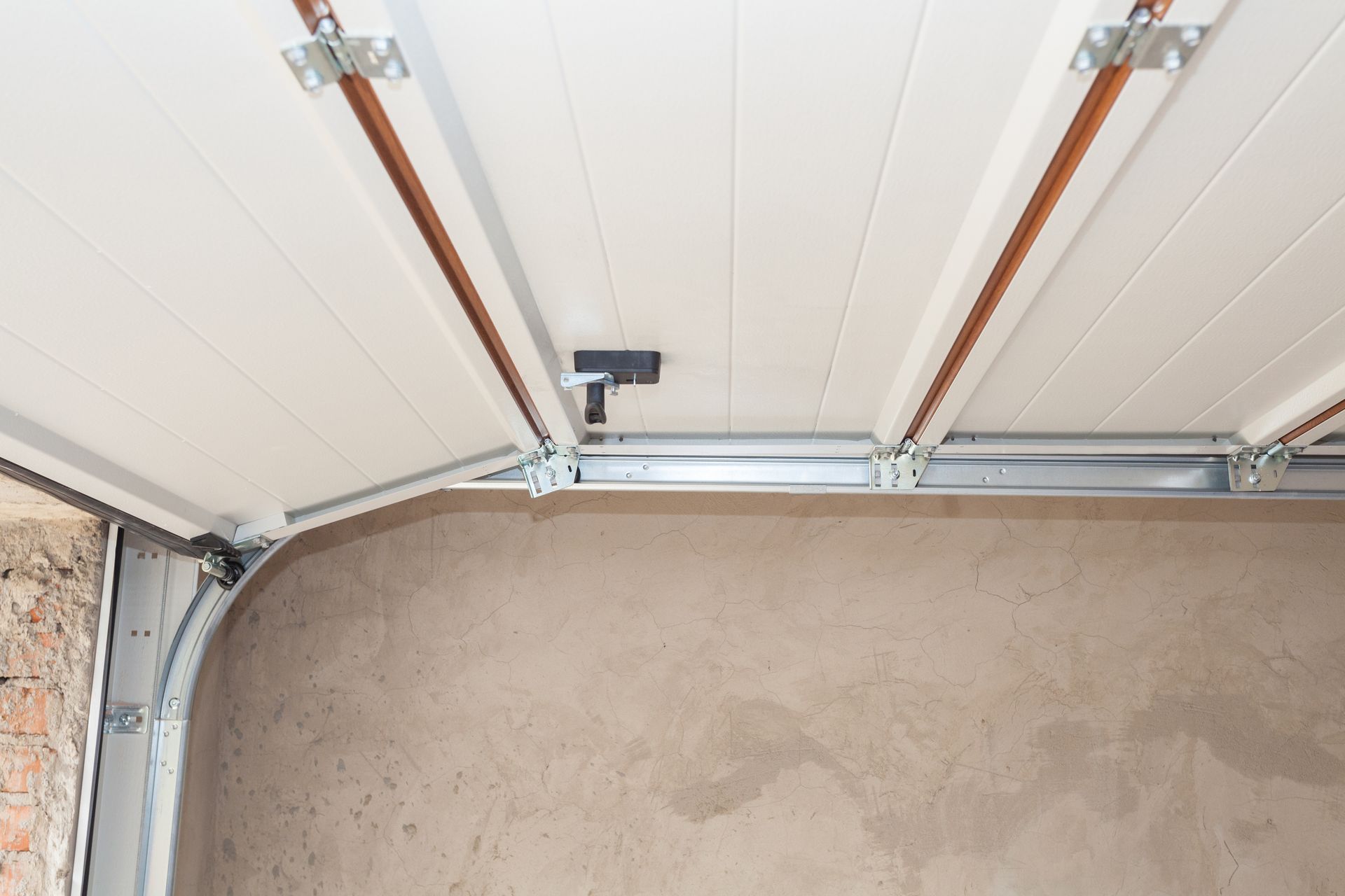Technician repairing a garage door torsion spring on a concrete driveway — garage door repair in Benton, LA