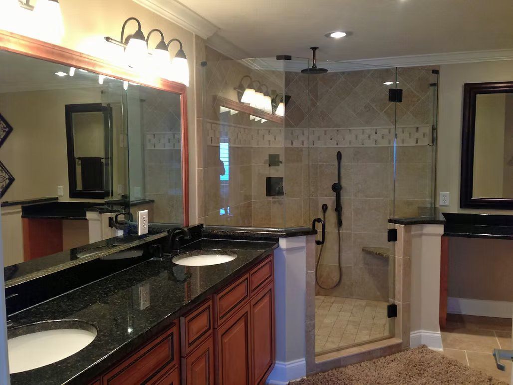 Bathroom with double vanity, granite countertop, and glass shower enclosure.