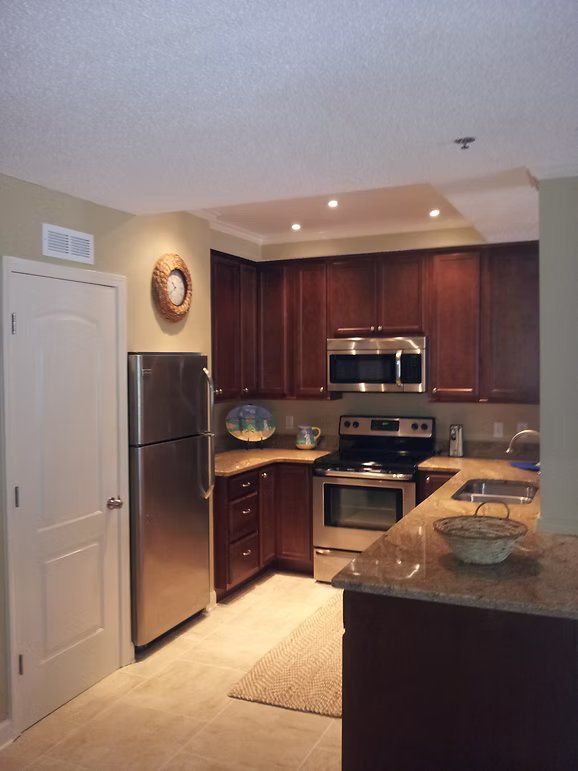 Kitchen with stainless steel appliances, dark wood cabinets, and light countertops.