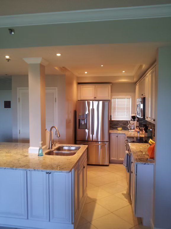 Kitchen with stainless steel refrigerator, white cabinets, and granite countertops.