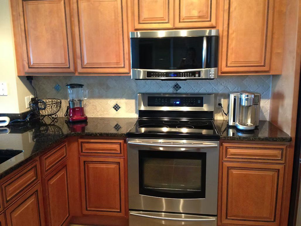 Kitchen with stainless steel oven, microwave, and brown cabinets with black trim.