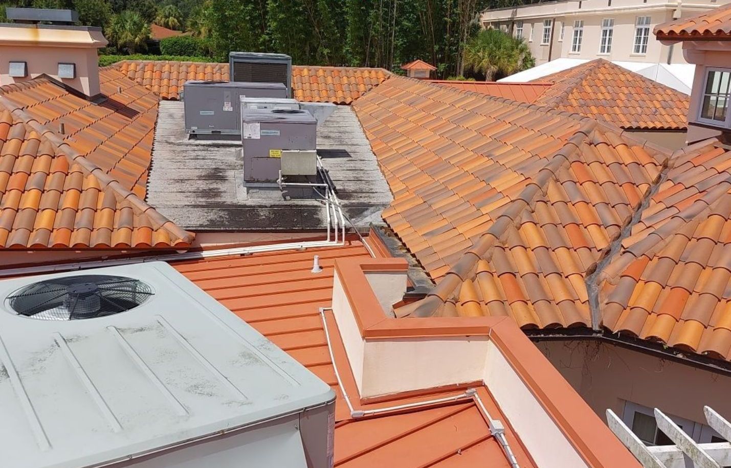 Orange-tiled rooftops with gray HVAC units in a residential neighborhood