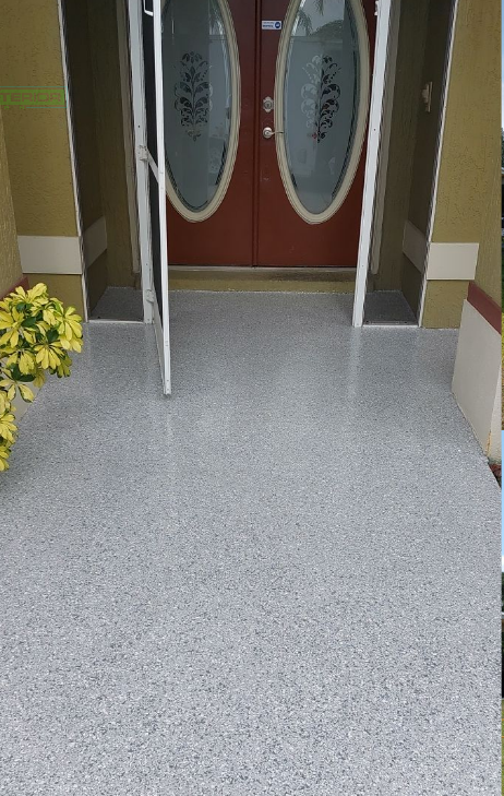 Entrance with double frosted-glass doors, tiled floor, and a potted yellow flower on the left.