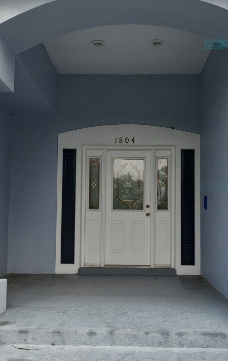 Blue-gray house entrance with white double doors and the number 1804 above the entryway