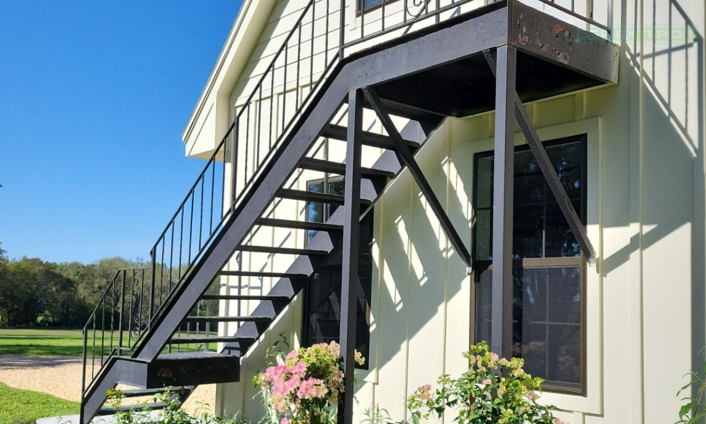 Exterior metal staircase beside a light-colored building under a blue sky