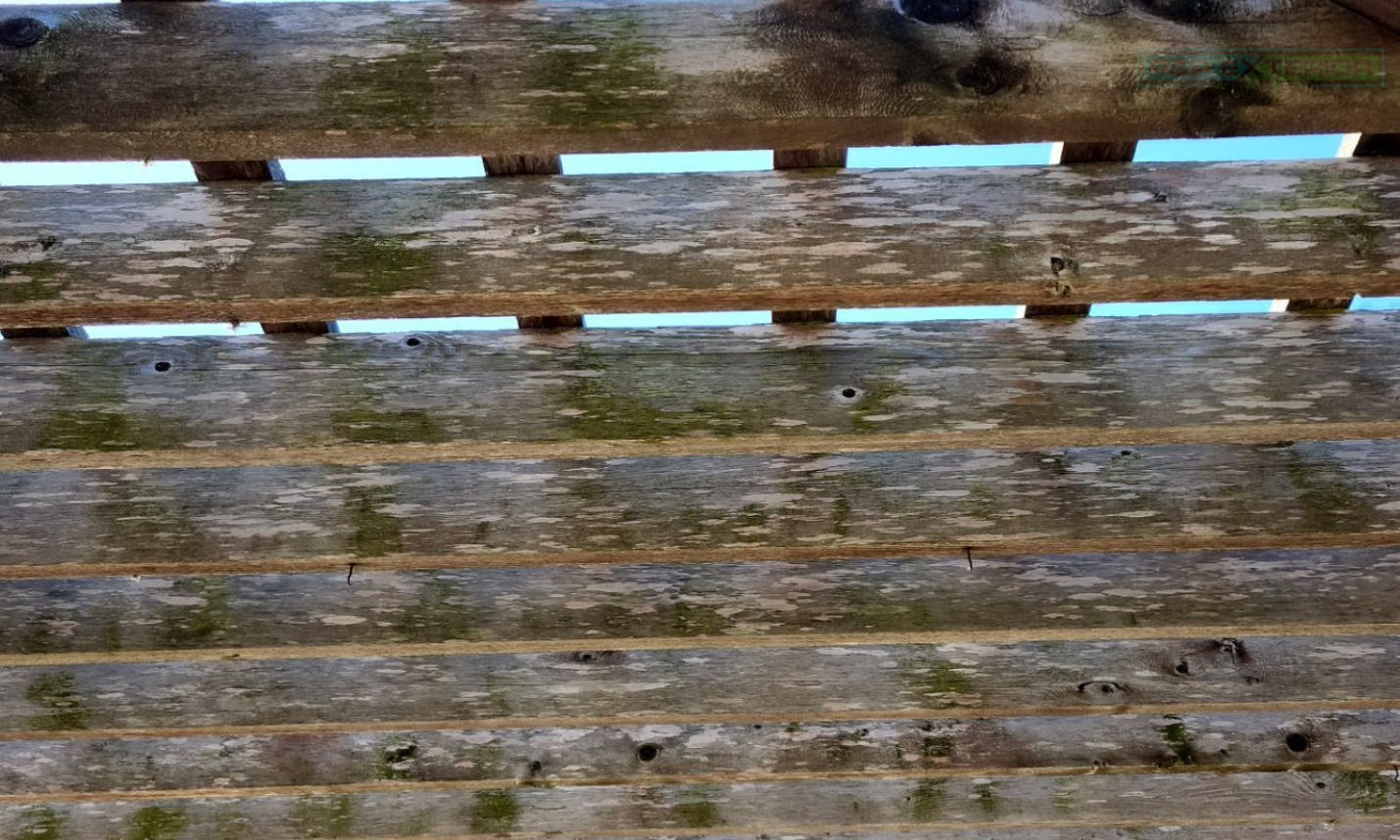 Weathered wooden fence with horizontal slats, some covered in snow, against a muddy ground background