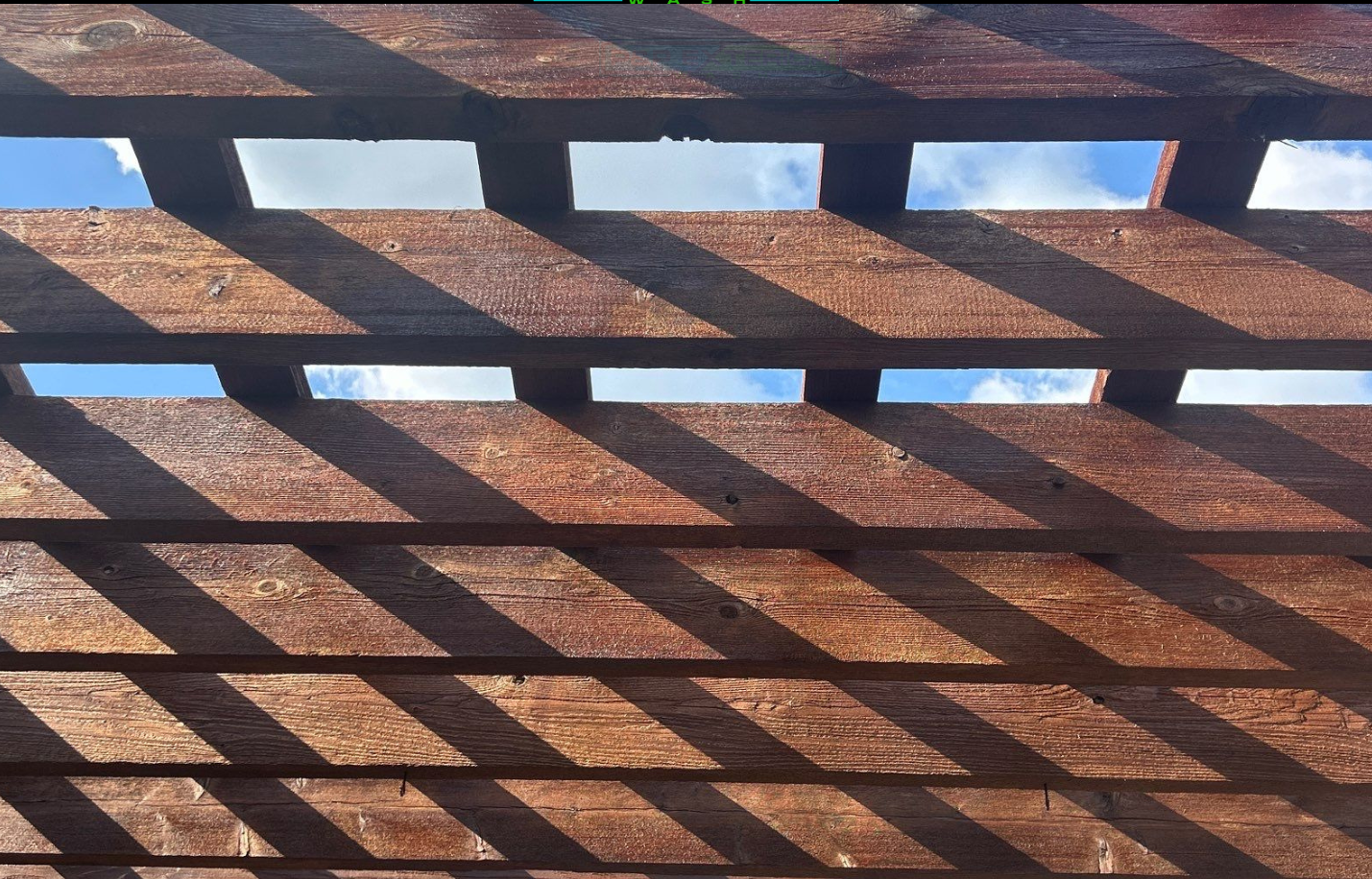 Sunlit brick lattice casting diagonal shadows against a blue sky