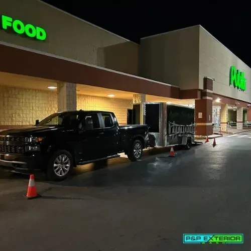 Nighttime storefront with a black pickup truck, shopping carts, and orange cones outside a Food/Pub building.