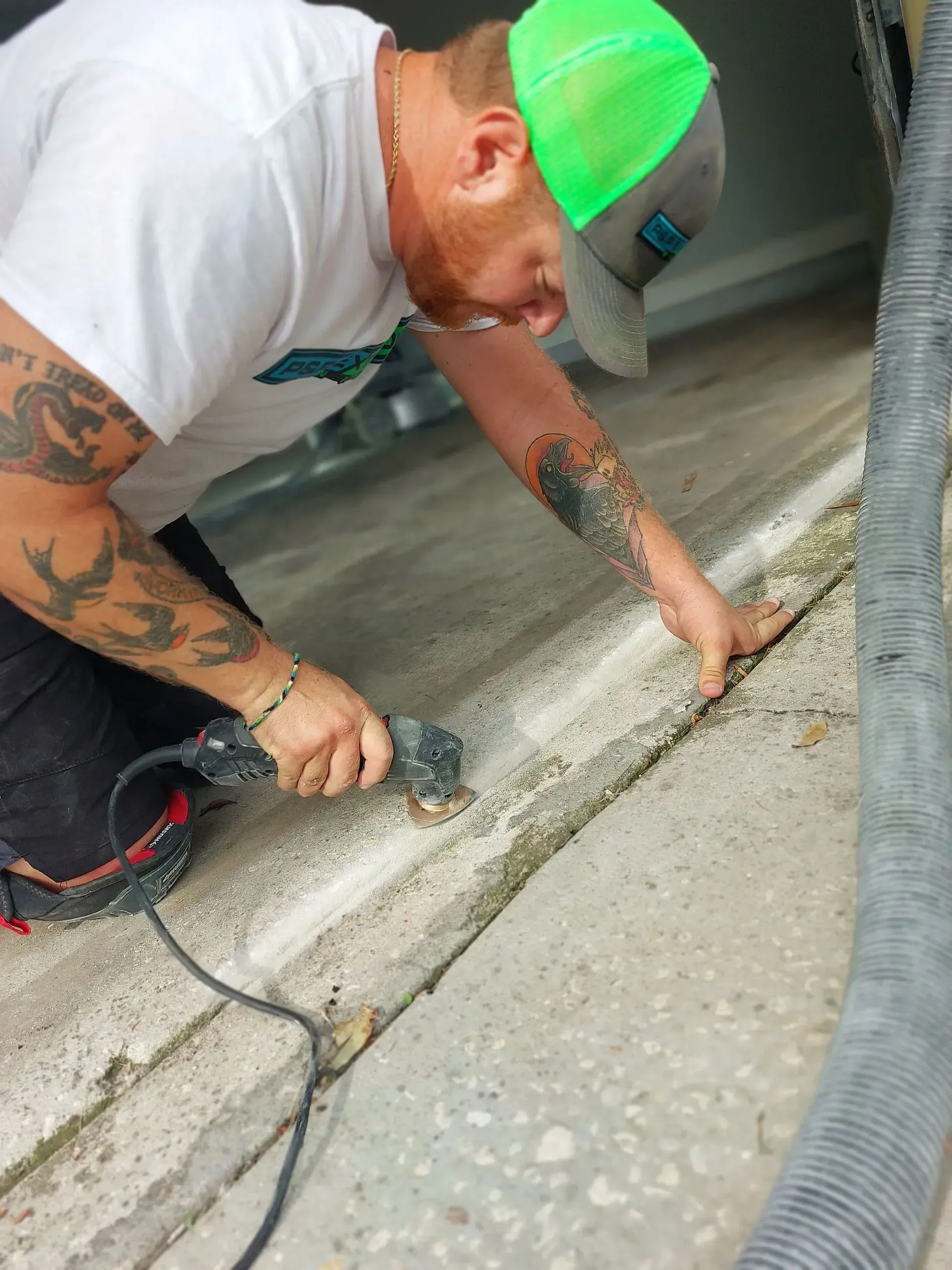 Worker in a neon green cap smoothing wet concrete on a driveway with a trowel