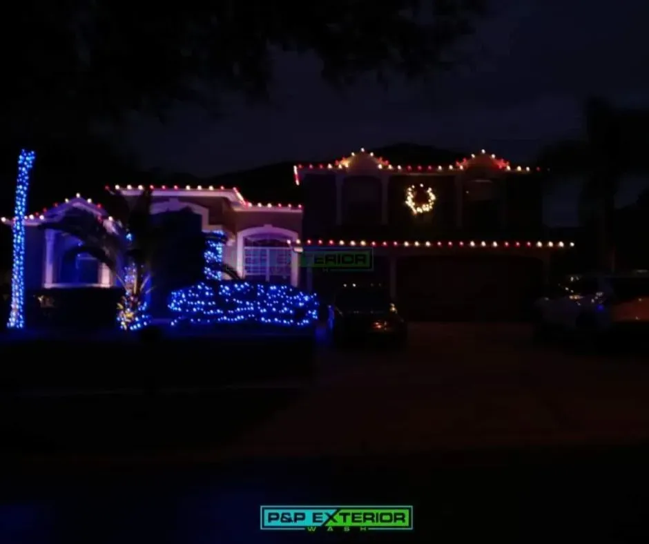 House lit with colorful Christmas lights at night, including blue, pink, and red decorations.