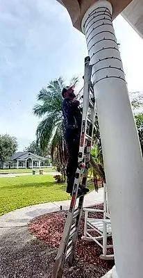 Person on a ladder cleaning a white column on a porch