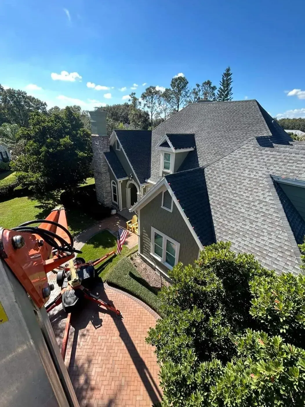 House roof being repaired by workers on a sunny day, seen from above.
