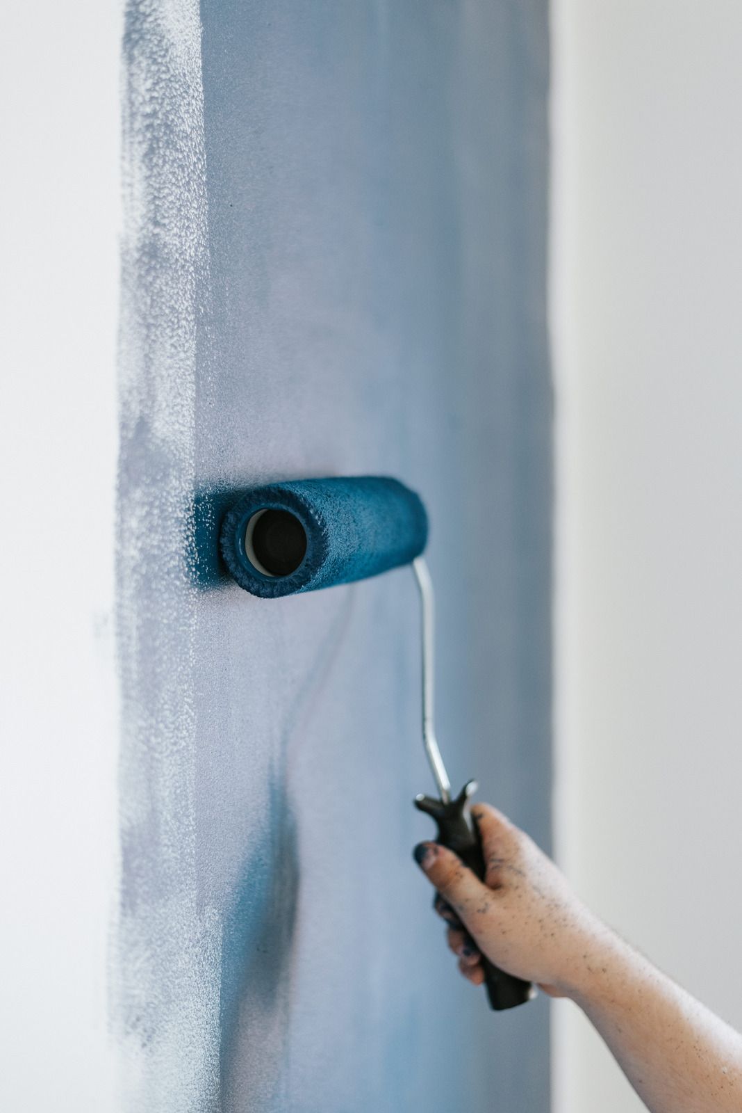 Hand painting a wall blue with a paint roller