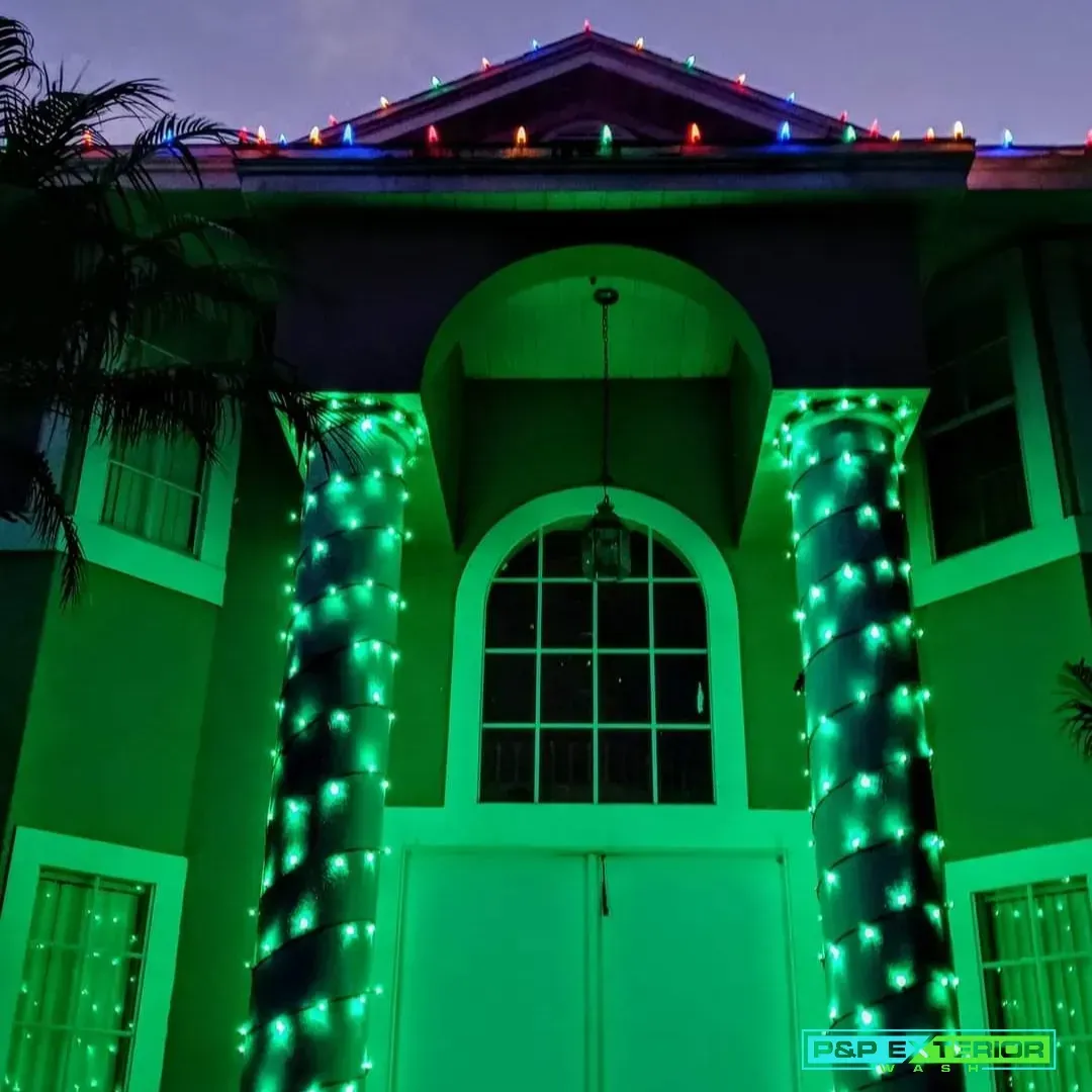 House entrance lit with green and multicolored holiday lights at night