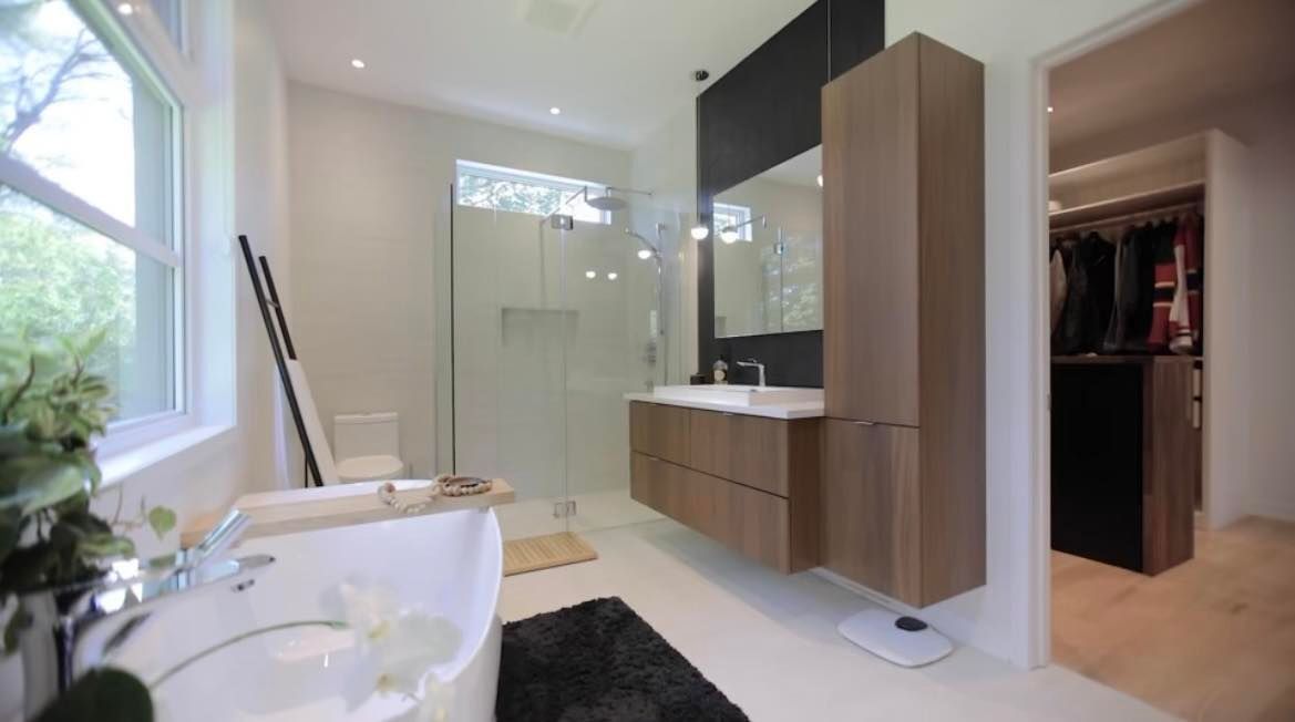 Salle de bain moderne avec vanité flottante, douche à l'italienne, baignoire blanche et accès au placard.