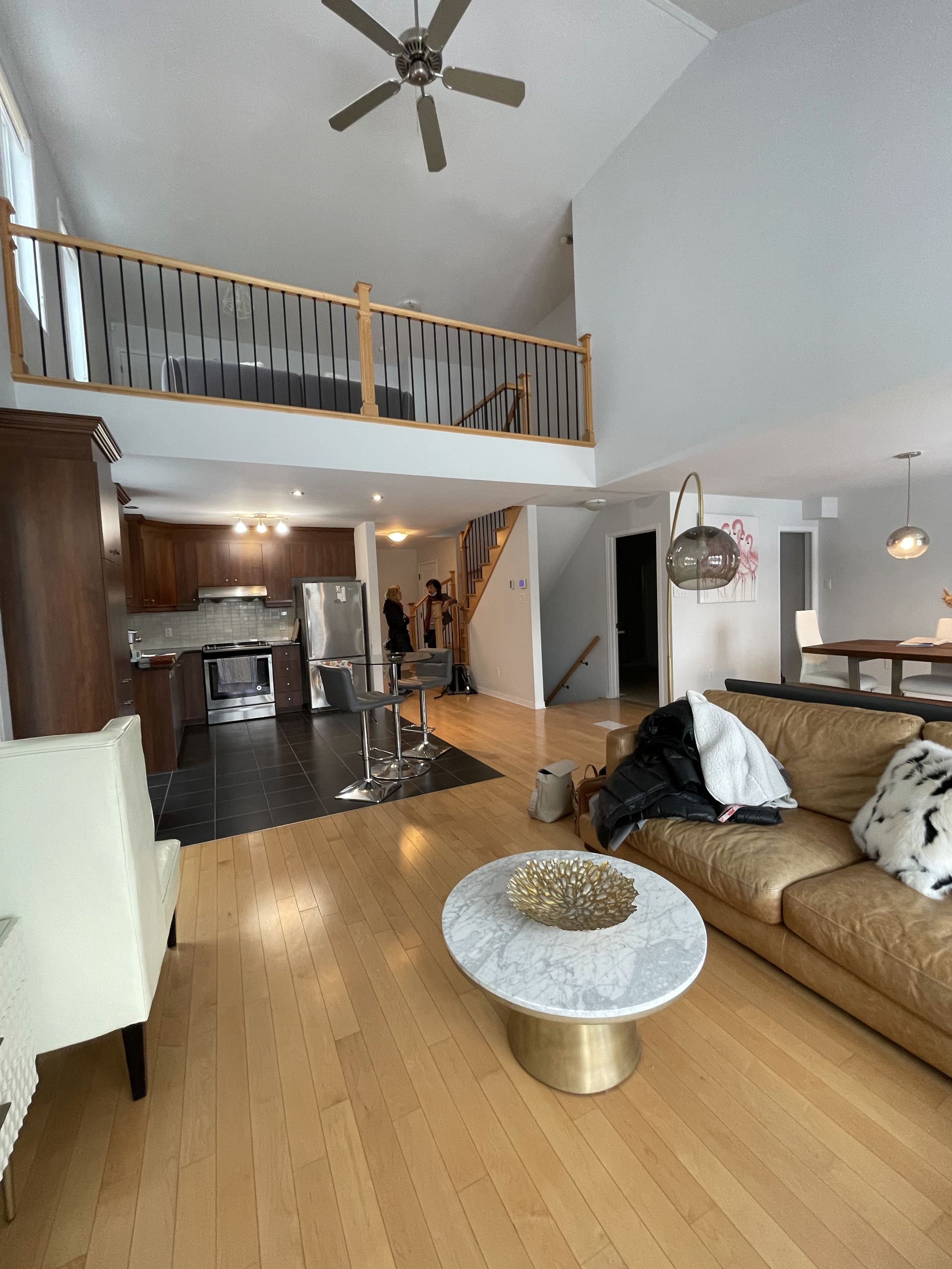 Séjour avec mezzanine, canapé en cuir marron, table basse en marbre blanc et cuisine en arrière-plan.