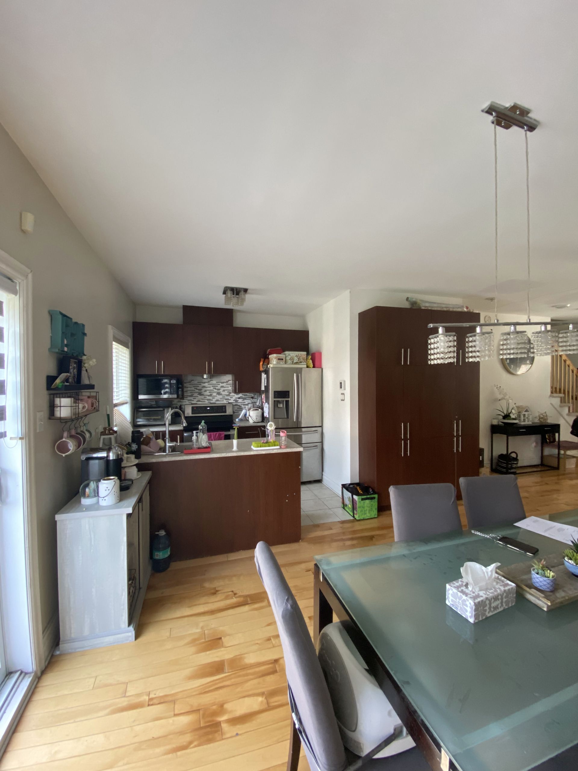 Cuisine moderne avec armoires marron foncé, parquet en bois clair et table à manger avec chaises grises.