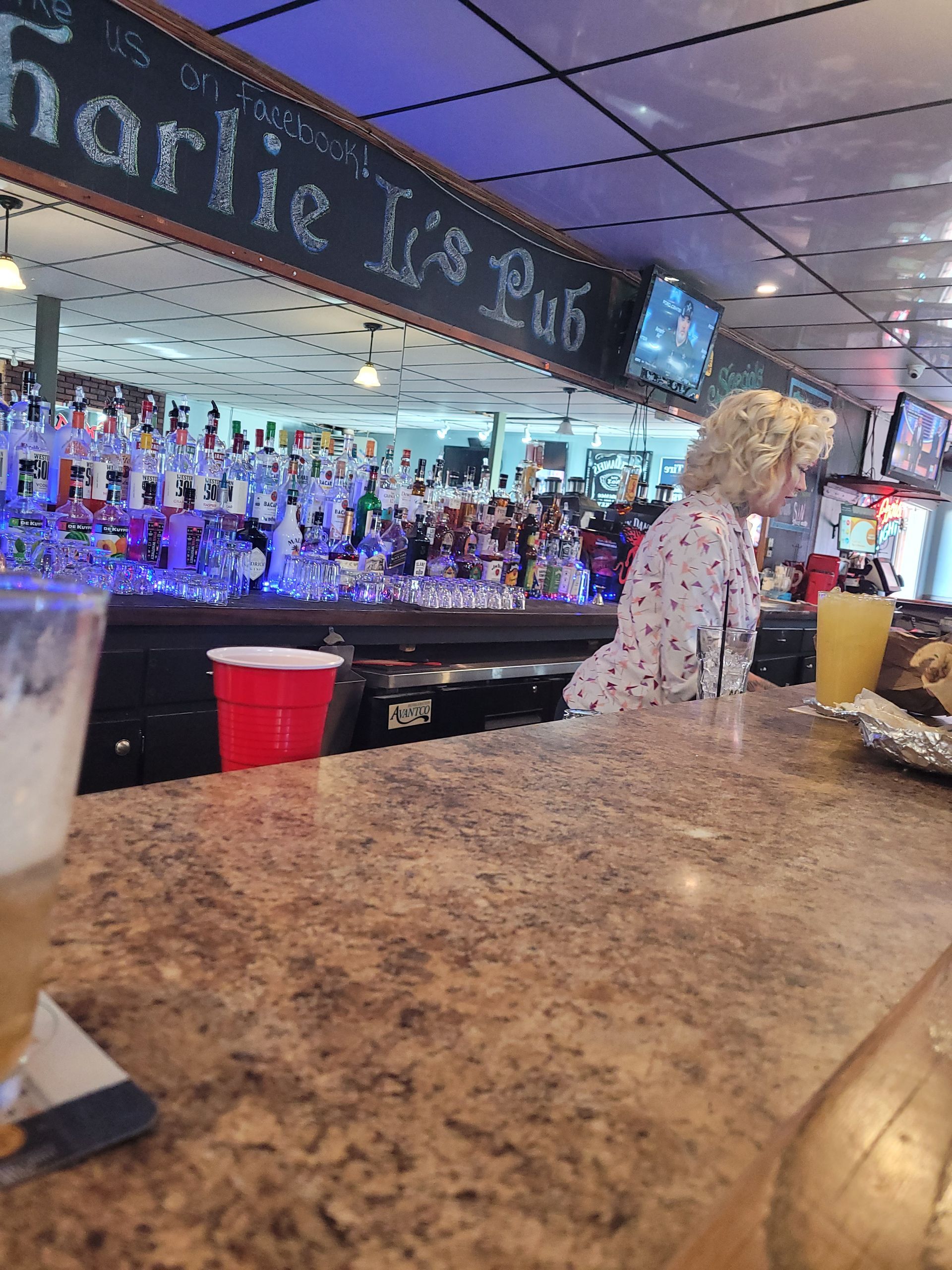 Bar counter with a bartender serving drinks in a lively, blue-lit restaurant or bar