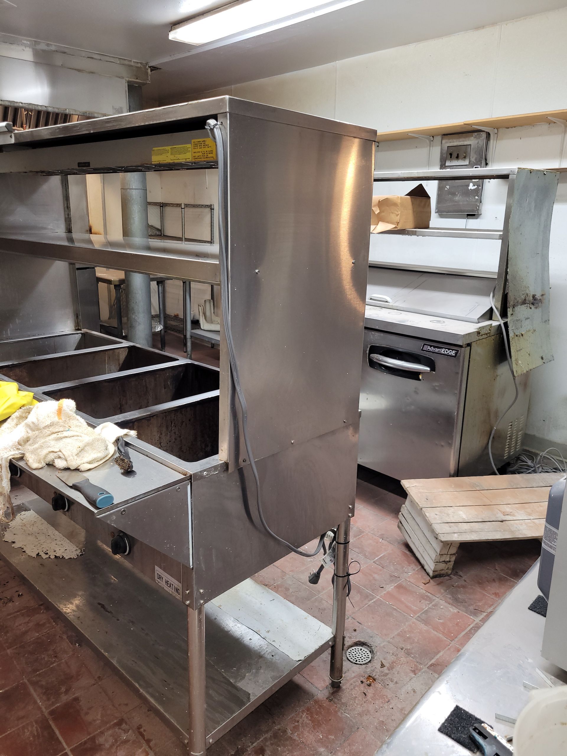 Stainless steel shelving and equipment in a cluttered commercial kitchen or prep area