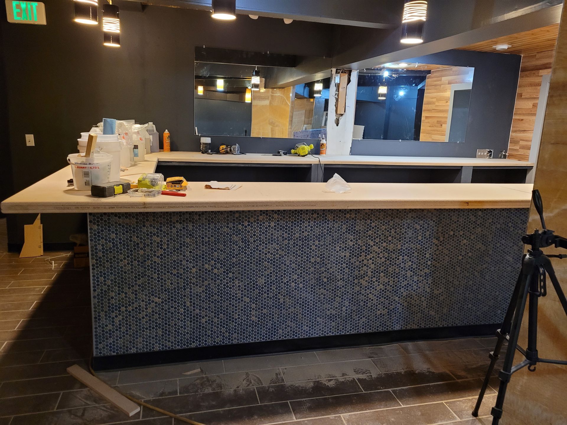 Empty hotel reception desk with black walls, white countertop, and a tripod on the right