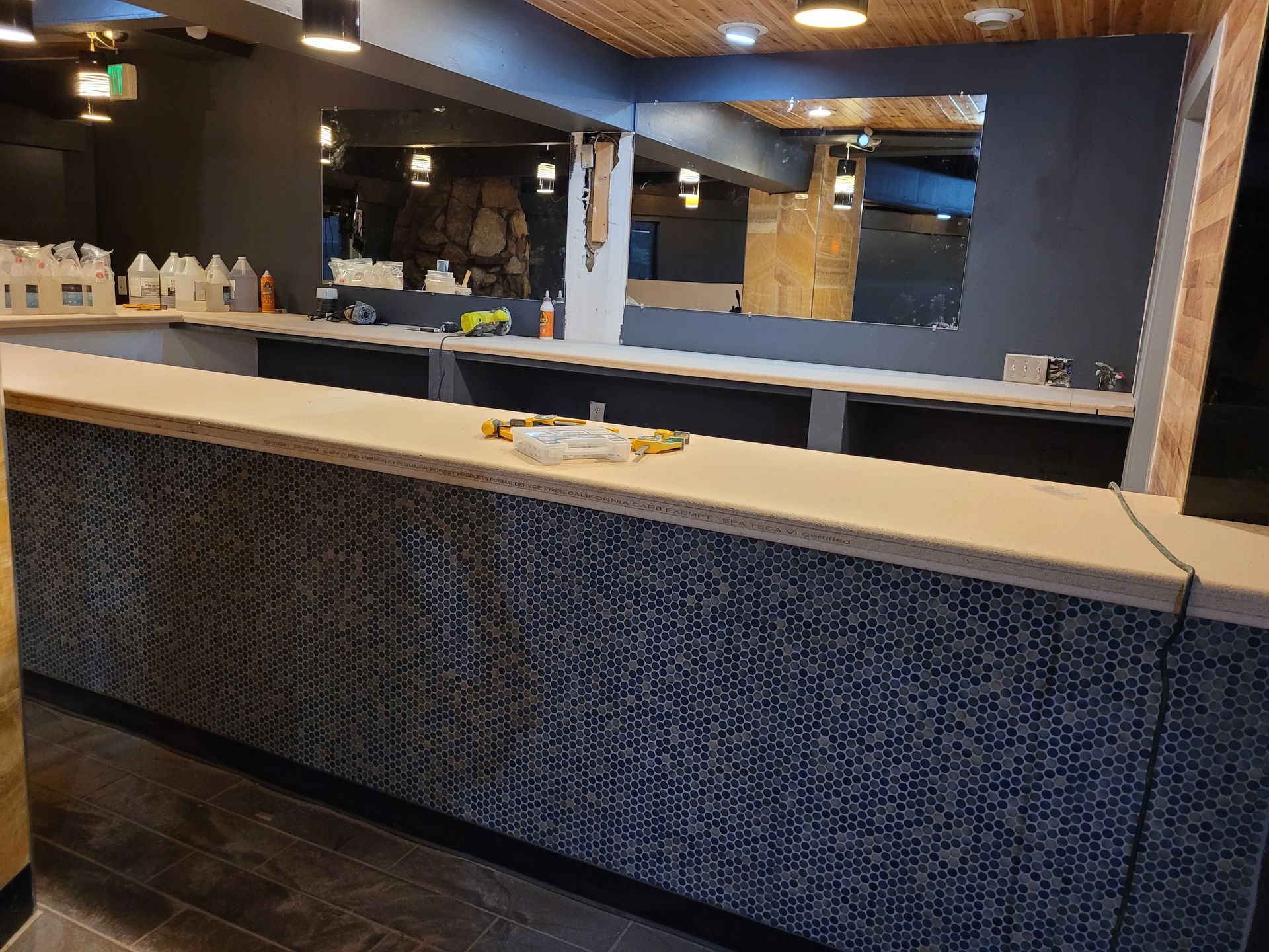 Empty bar counter in a modern restaurant interior with dark tiled front and warm ceiling lights